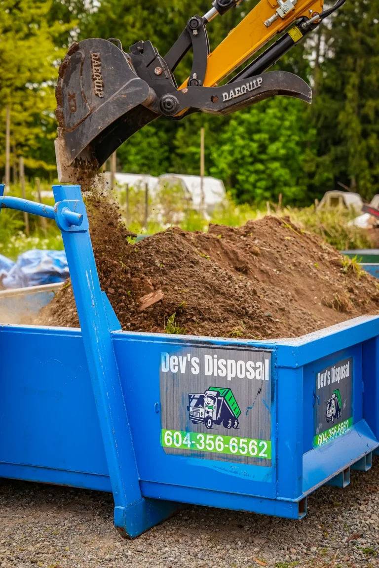 Excavator filling a blue dirt bin during a soil removal job in the Fraser Valley, Mission BC.